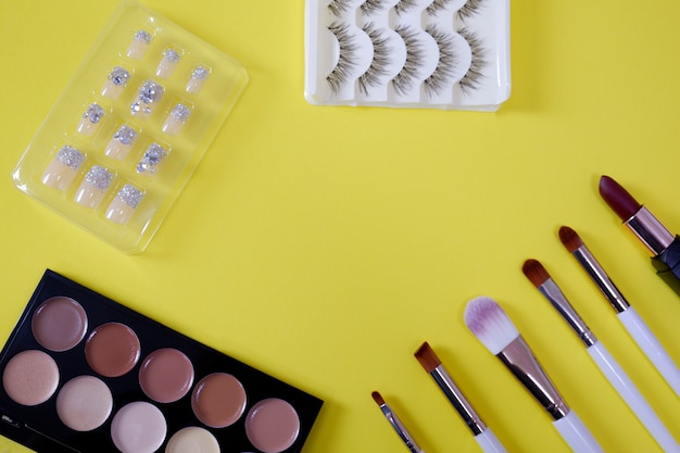 Top view of womenâs cosmetic on yellow background.