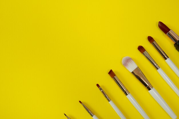 Top view of womenâs cosmetic on yellow background.