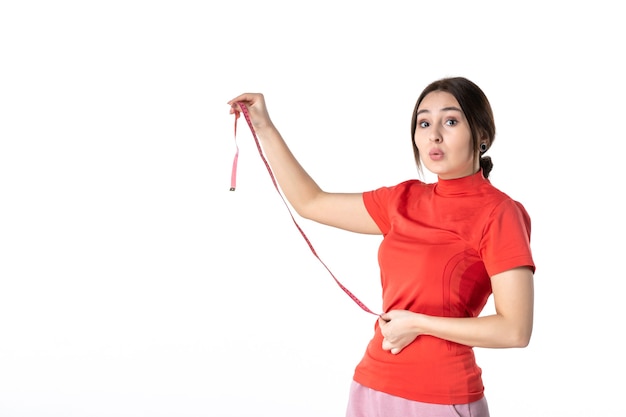 Vista dall'alto di una giovane ragazza che si chiede in camicetta redorange e che tiene il misuratore su sfondo bianco