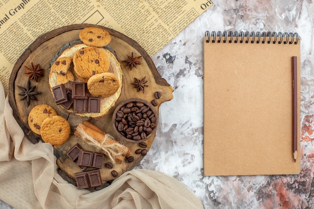 볶은 커피 콩 초콜릿 코코아 그릇 계피 스틱 공책과 연필 테이블에 쿠키 그릇과 상위 뷰 나무 소박한 보드
