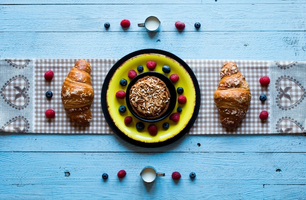 Top view of a wood table full of cakes, fruits, coffee, biscuits, spices and more