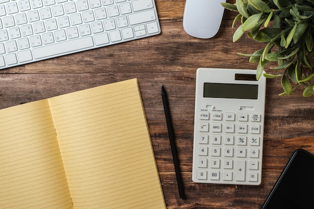 Top view wood table with calculator and notebook working desk at home