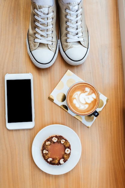 Top view of wooden board with phone, coffee