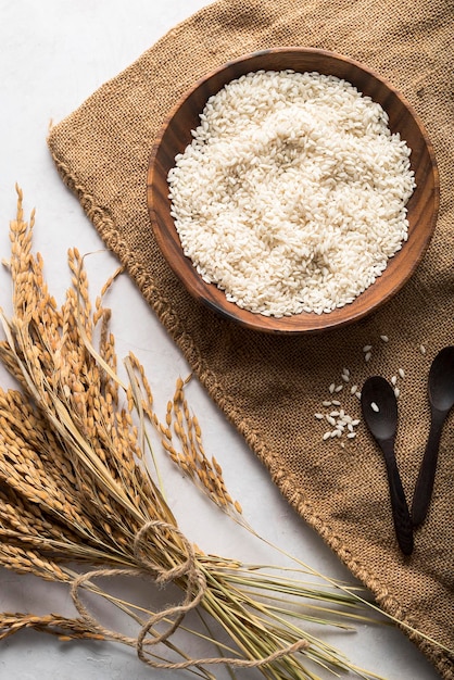 Foto vista dall'alto di una ciotola di legno di riso e orecchie di riso cibo naturale ricco di proteine