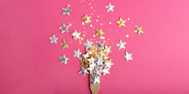 Top view of the wooden brush on the pink background,with silver and golden stars above.Festive shining bokeh.Large banner with copy space.