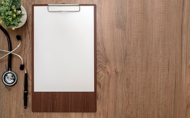 Top view wooden clipboard with blank a4 paper and stethoscope on wooden table