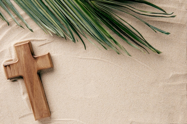 Top view wooden cross and leaf on sand arrangement