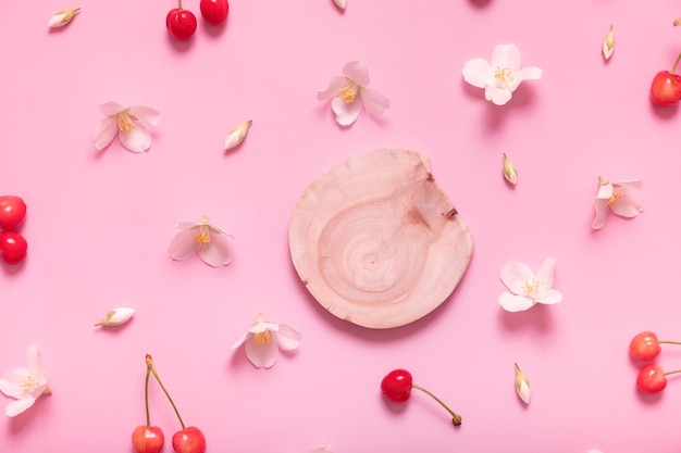 Top view wooden podium or pedestal with jasmine flowers and sweet cherry on pastel pink background e