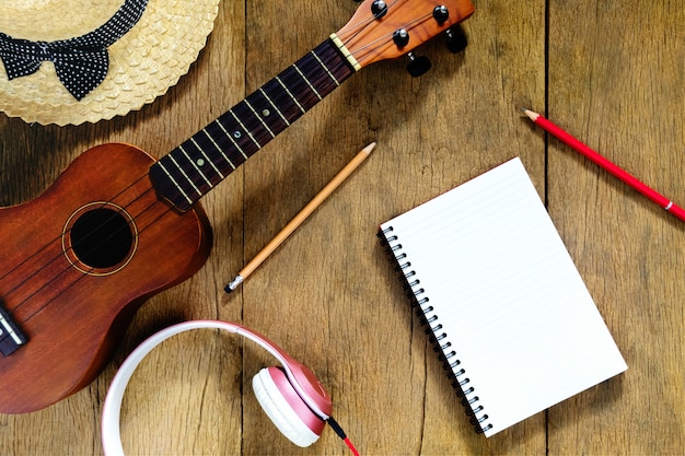 Top view wooden table, There are notebooks, pencils, hats, earphones, and ukulele 