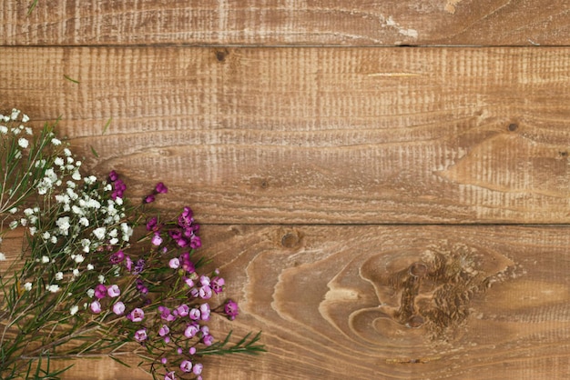 Top view of a wooden table on which fresh flowers lie in the corner copy space