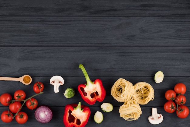 Top view on wooden table with italian products peppers, tomatoes, pasta. Copy space for text.