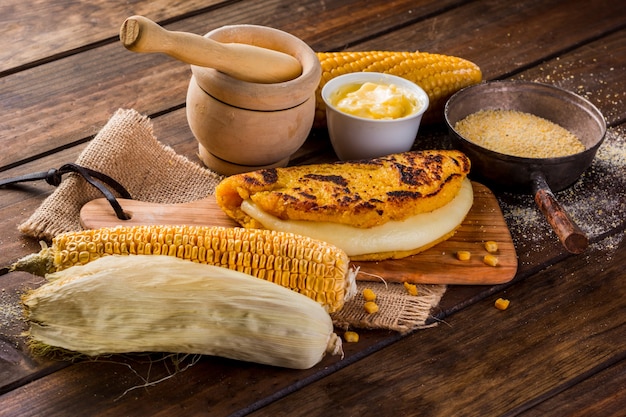 Top view of a wooden table with several ingredients for the preparation of Cachapas with cheese