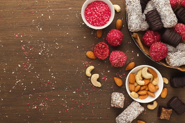 Top view on wooden table with variety of healthy raw vegan candies, almonds, hazelnuts, dates. Fitness dessert and eating right concept, copy space