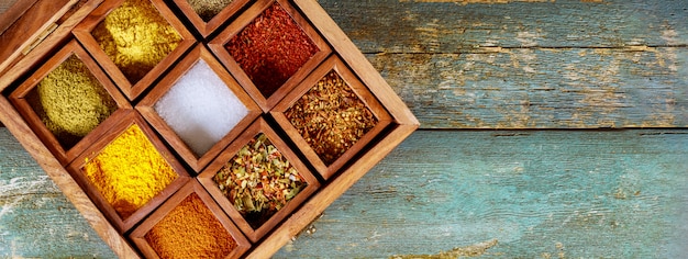 Top view of wooden tray filled with full of ground colorful spices