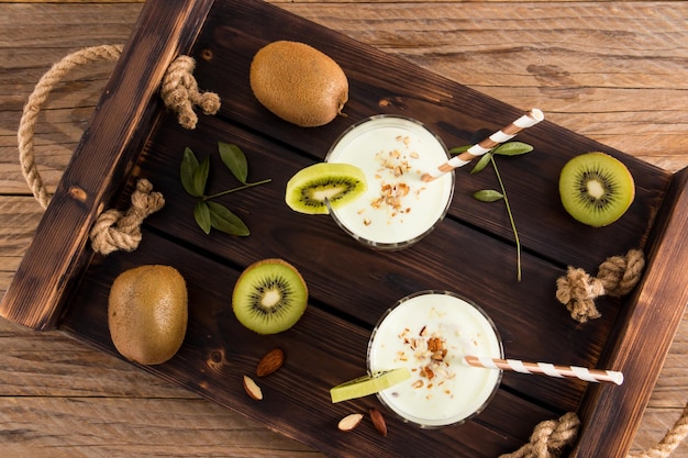 Top view of a wooden tray with two glasses of healthy homemade fruit smoothie detox is a healthy drink for energy and wellbeing