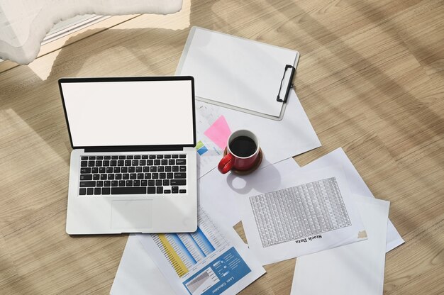 Photo top view of work place with blank screen laptop, document and coffee cup on wooden floor.