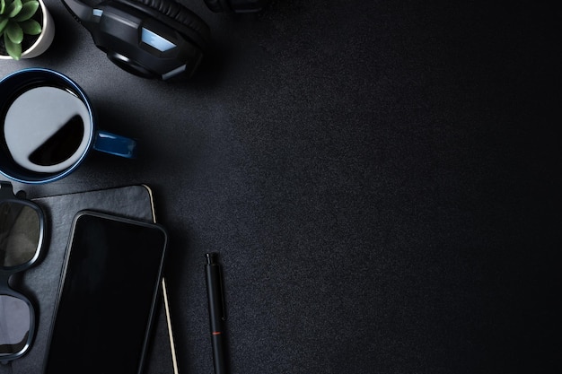 Top view working desk with keyboard headphone and mobile phone on black table background