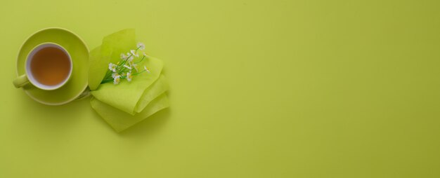 Top view of workspace with copy space, tea cup and decoration on green table