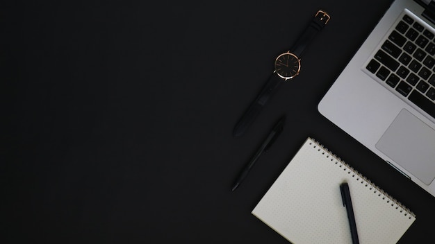 Area di lavoro vista dall'alto con orologio con penna per laptop e taccuino nero