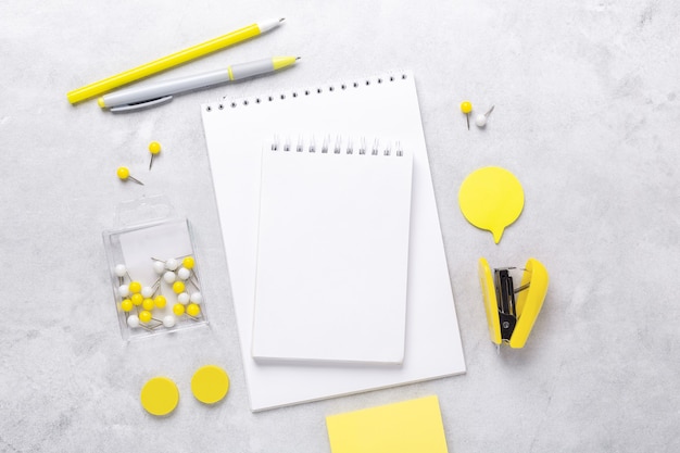Top view of workspace with notepad and stationery accessories on gray stone background. Illuminating Yellow and Ultimate Gray, colors of the year 2021 - Image