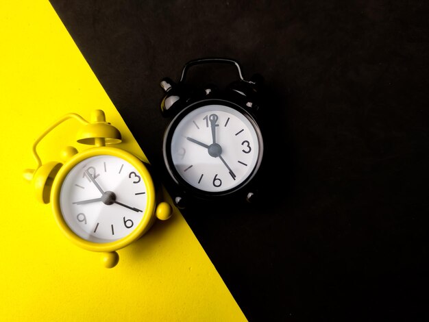 Top view yellow and black alarm clock on a yellow and black background with copy space