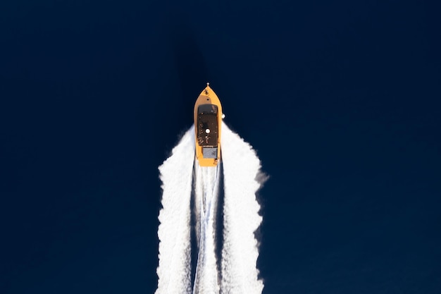 Top view of a yellow boat sailing on dark blue water