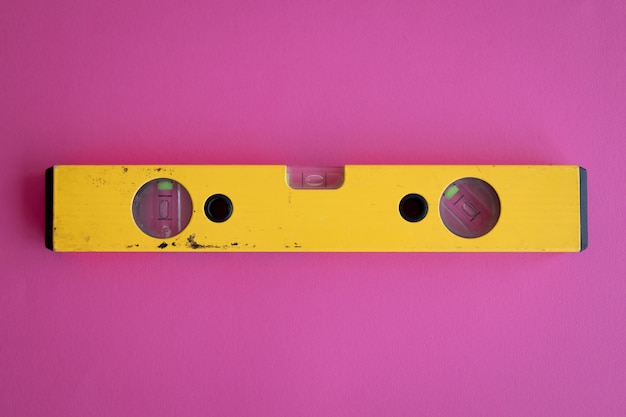 Photo top view of a yellow measuring tool on a pink backgroud