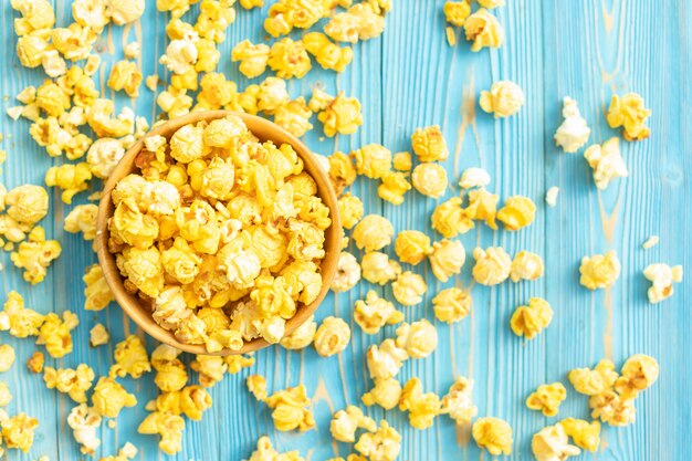 Top view of yellow popcorn on blue wooden planks