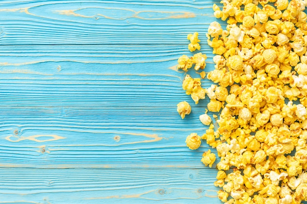 Top view of yellow popcorn on blue wooden planks