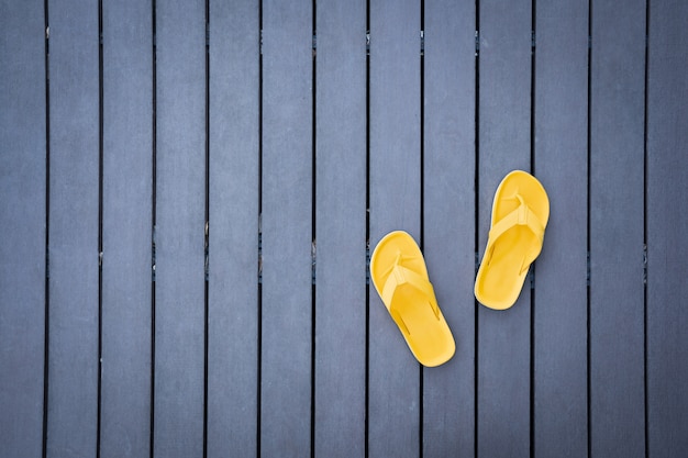 Top view of yellow slippers on dark wooden slats floor