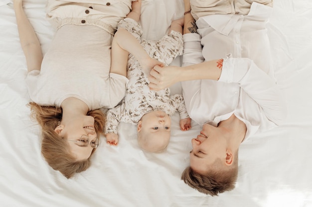 Top view of young happy smiling family with awesome little plump blueeyed baby infant toddler lying