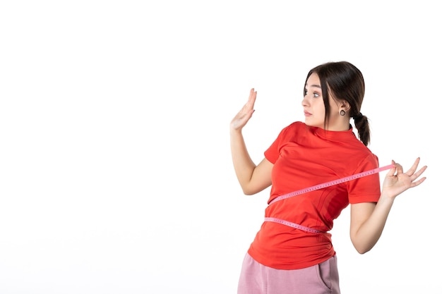 Top view of a young lady gathering her hair dressed in redorange blouse and holding metre measuring her waist feeling scared on white background