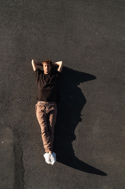 Photo top view of young man carefree lying on the asphalt