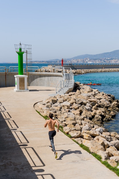 海の近くの遊歩道に沿って走っている若い男の上面図