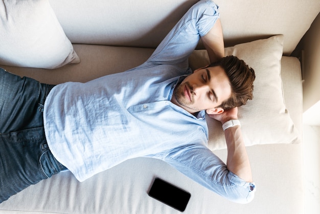 Photo top view of a young man sleeping on the couch