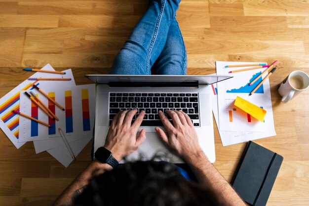 Top view of Young man working with his laptop from his living room. Stay at home, work from home concept