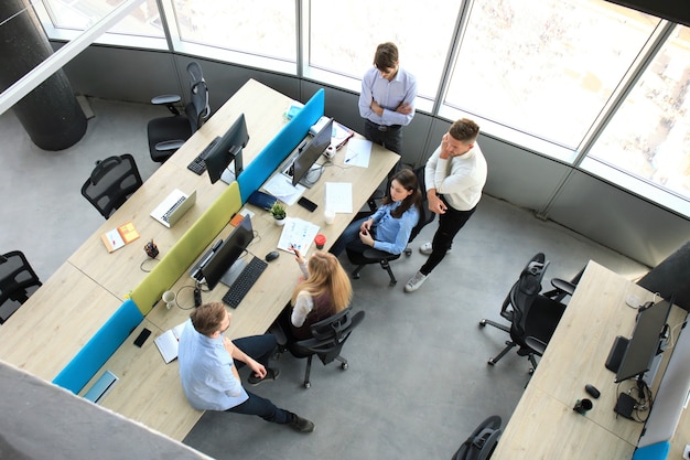 Foto vista dall'alto di giovani colleghi moderni in abbigliamento casual intelligente che lavorano insieme mentre trascorrono del tempo in ufficio.