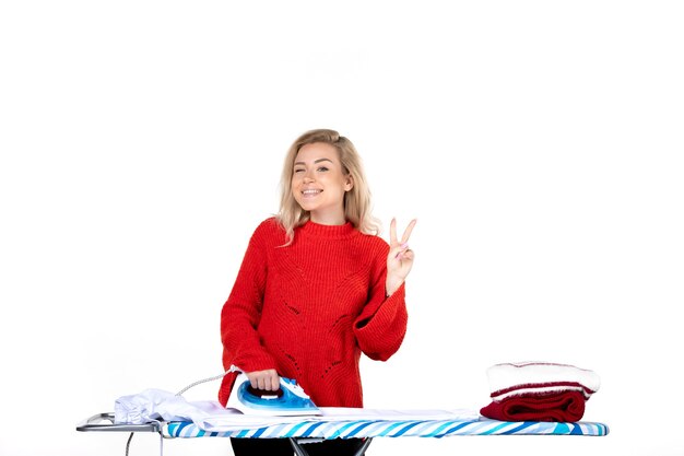 Top view of young smiling beautiful woman ironing clothes making victory gesture on white background