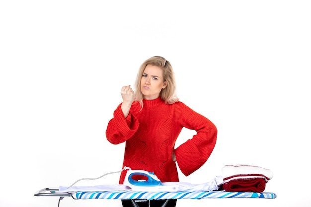 Top view of young unhappy beautiful woman ironing clothes and feeling angry about something on white background