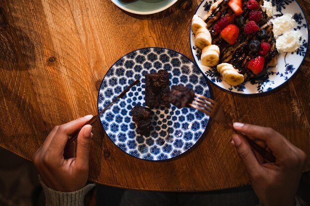 Top view of young woman eating a glutenfree chocolate brownie during a brunch in a cafeteria