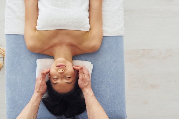 Top view Young woman is lying down when man doing massage of her body at spa