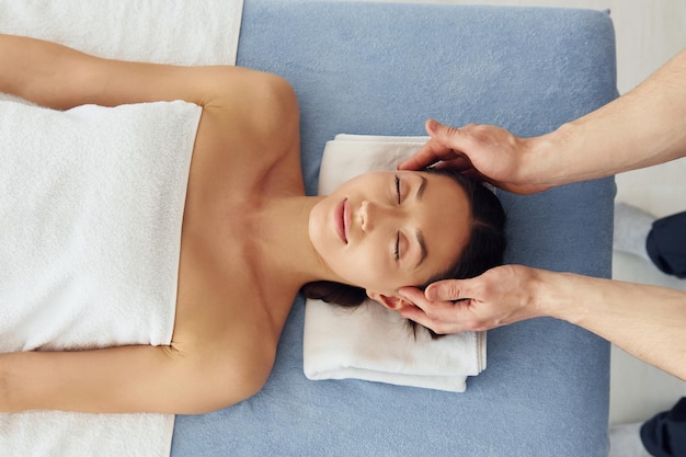 Foto vista dall'alto la giovane donna è sdraiata quando l'uomo fa il massaggio del suo corpo alla spa