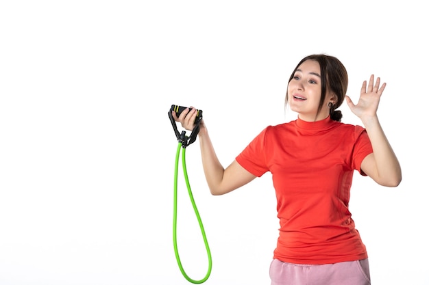 Top view of a young woman neatly gathering her hair dressed in redorange blouse and holding rope sport accessory saying hello to someone on white background