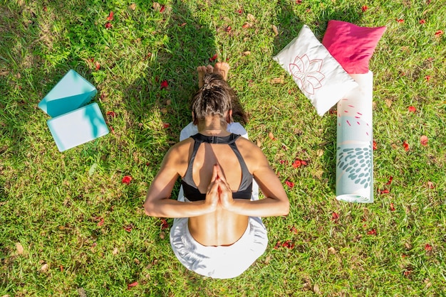 Photo top view of young woman practicing yoga on a green meadowsitting and bending forward