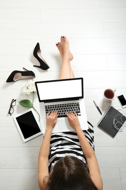 Top view of young woman sitting on floor with laptop