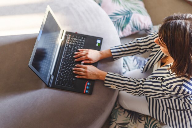 Top view of young woman sitting on floor with laptop