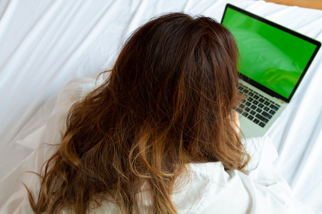 Photo top view young woman use laptop on the bed