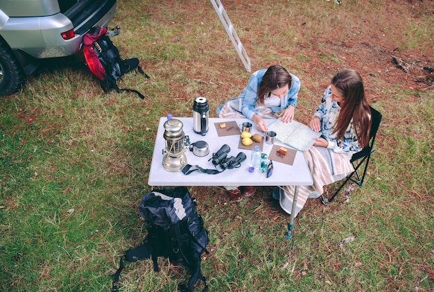 Top view of young women looking road map in a campsite