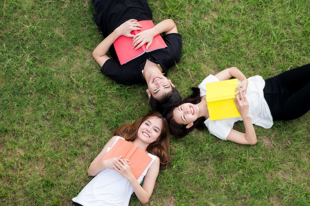 Top viewof group of Asian student lying with notebook and looking away. 