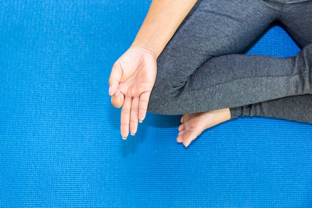 La giovane donna attraente di viste superiori che risolve a casa, facente l'esercizio di yoga sulla stuoia blu